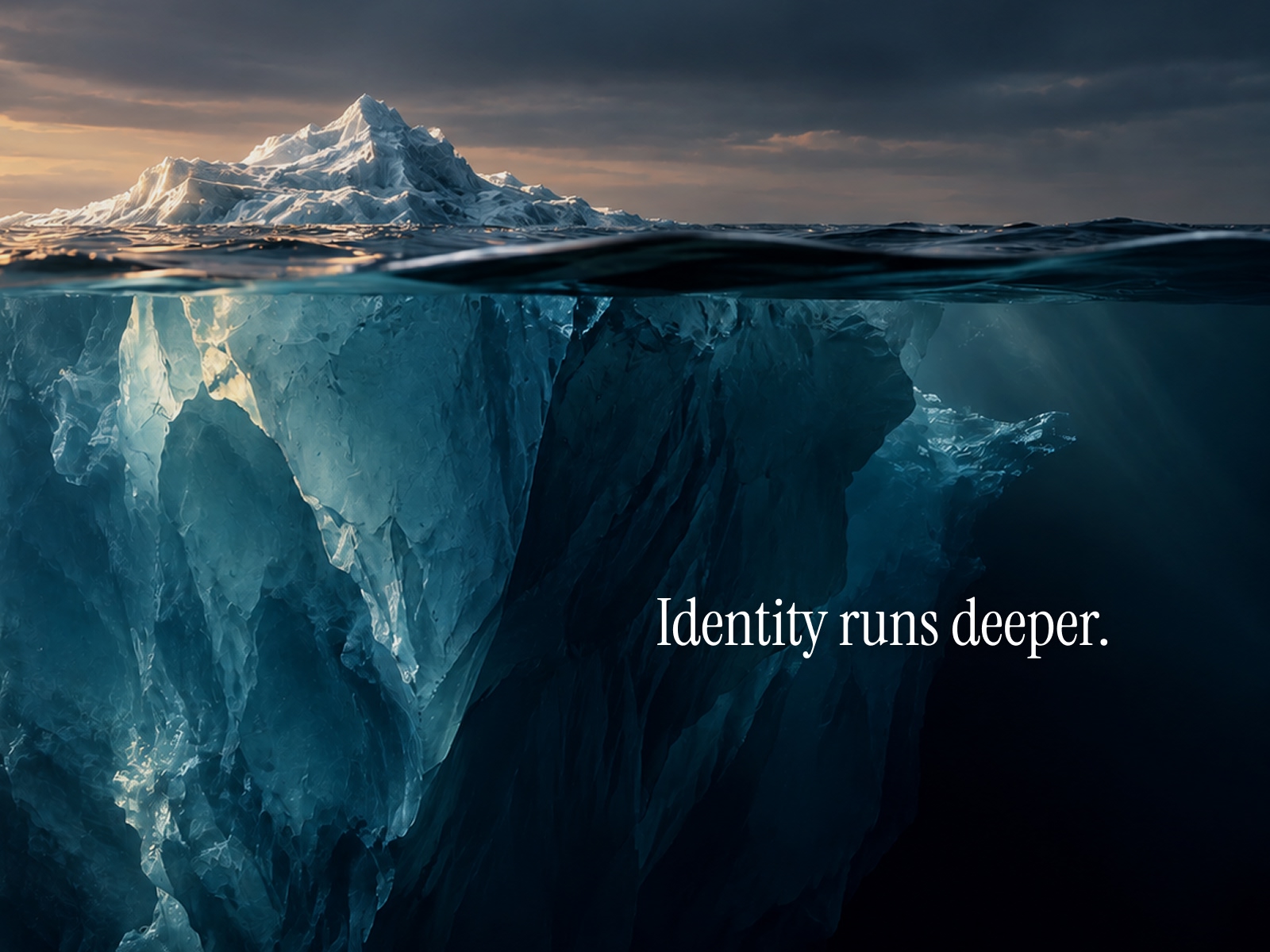 A striking iceberg rises above the ocean, revealing an immense, intricate structure hidden beneath the surface. Accompanied by the words ‘Identity runs deeper.’, the image offers a visual metaphor for brand identity.